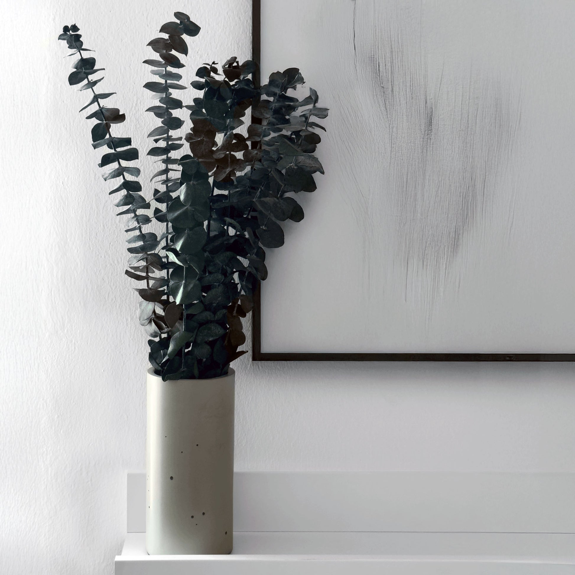 Blumenvase ALEA aus Beton auf einem Wandregal gefüllt mit Eukalyptus